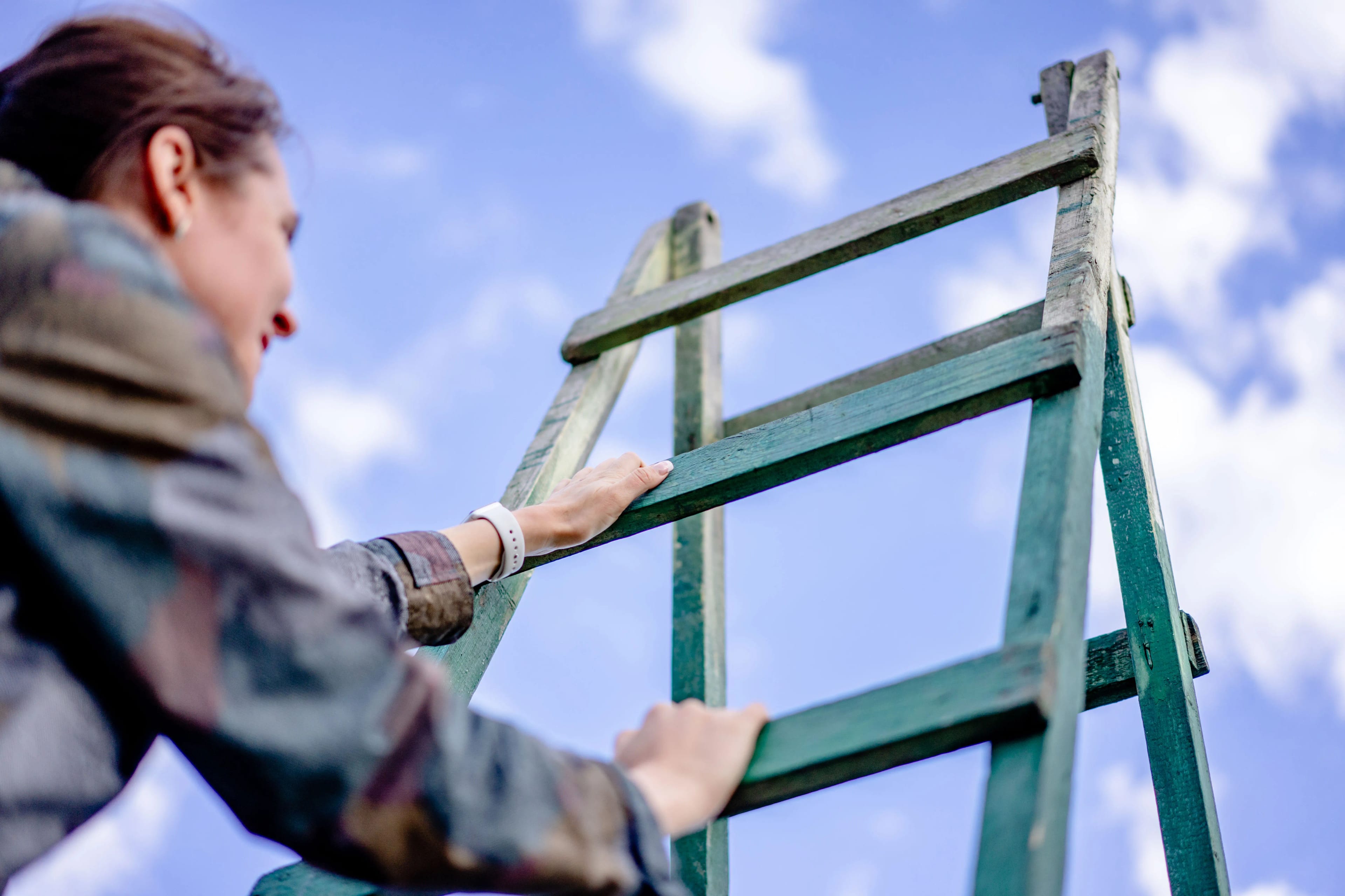 Person climbing a ladder toward the sky, representing personal growth and reaching new potential.