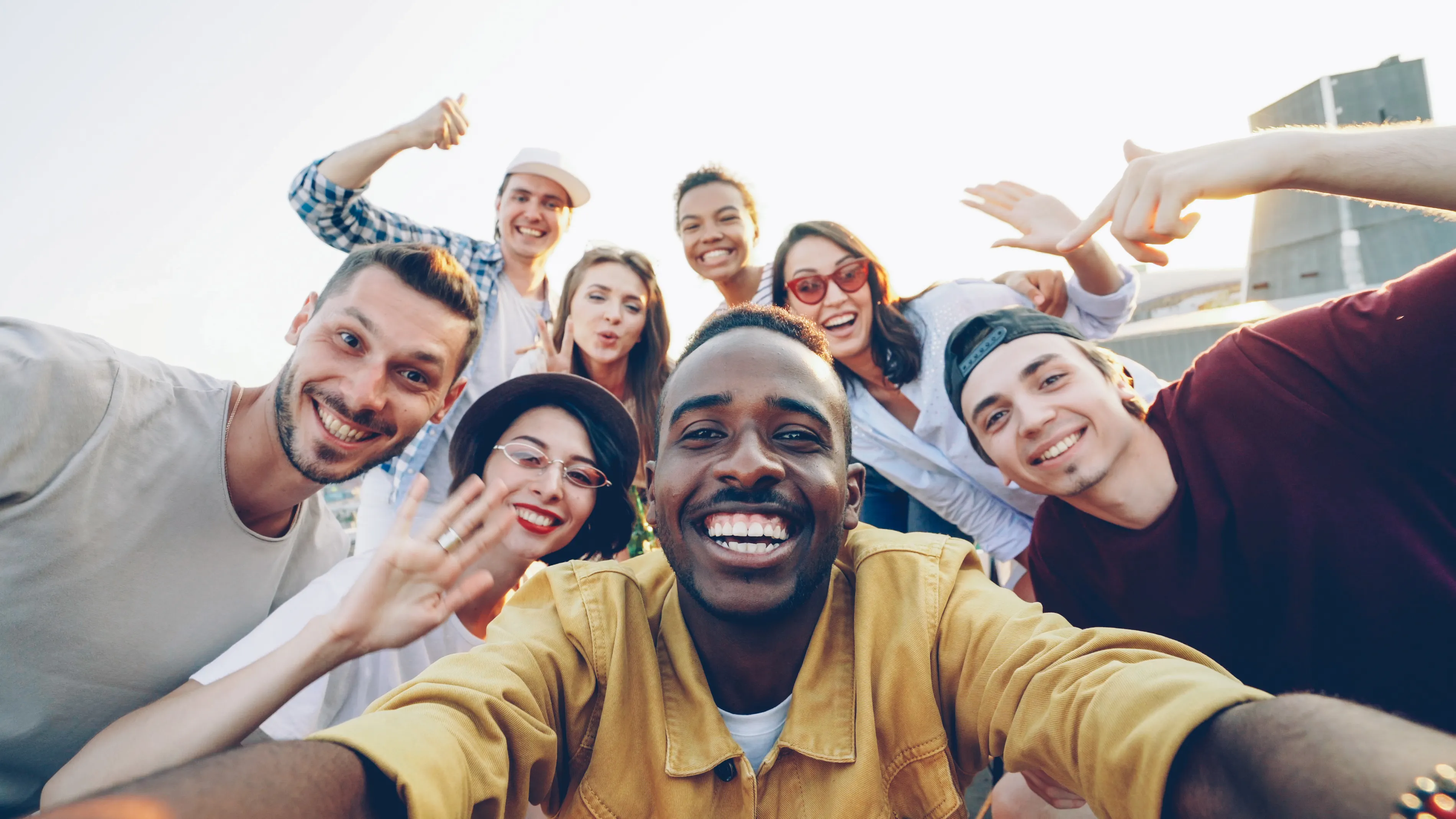 A group of friends smiling and taking a selfie together outdoors, reflecting the role of social connection in happiness.