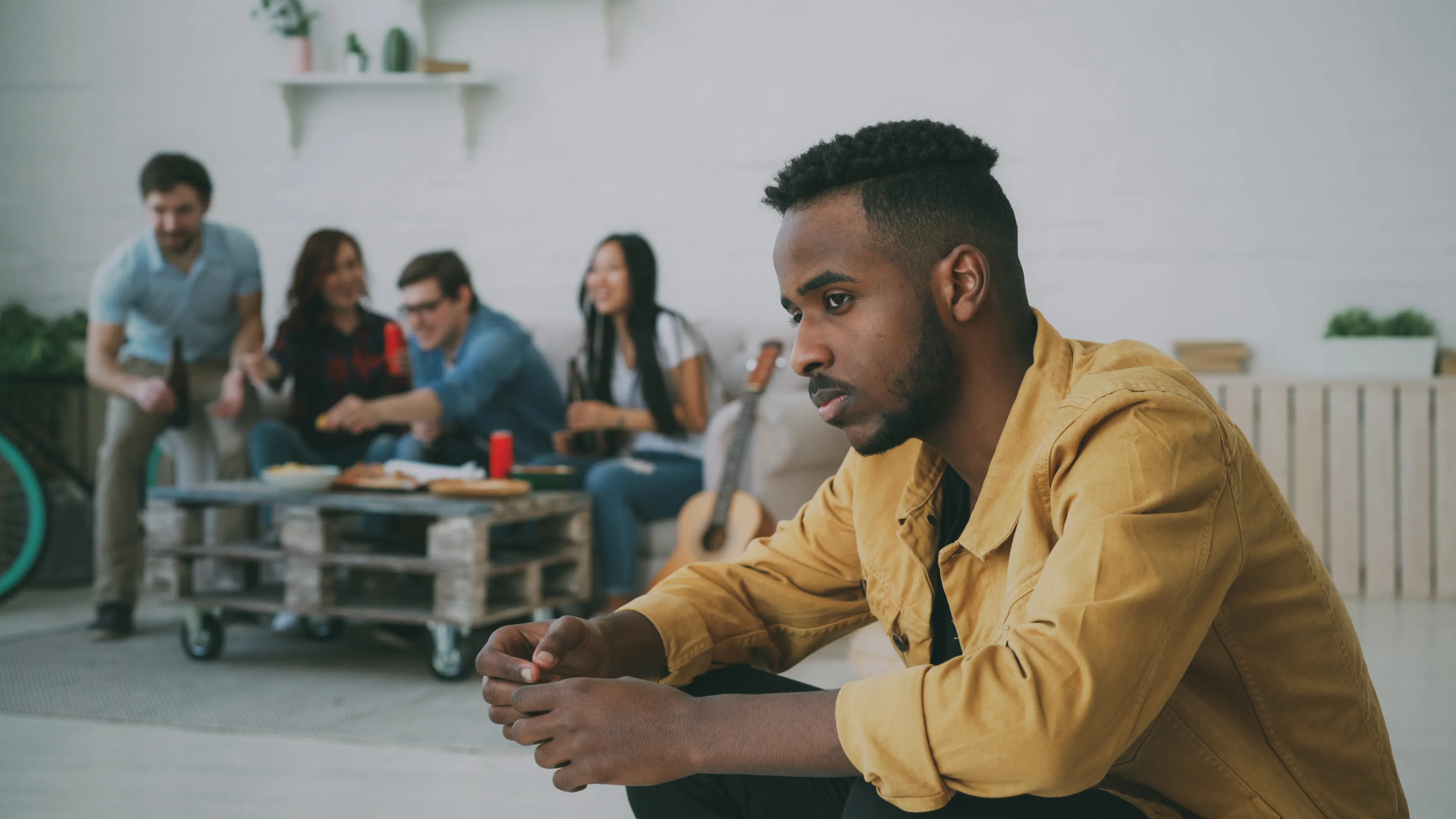 Man feeling jealous while watching friends celebrate in the background