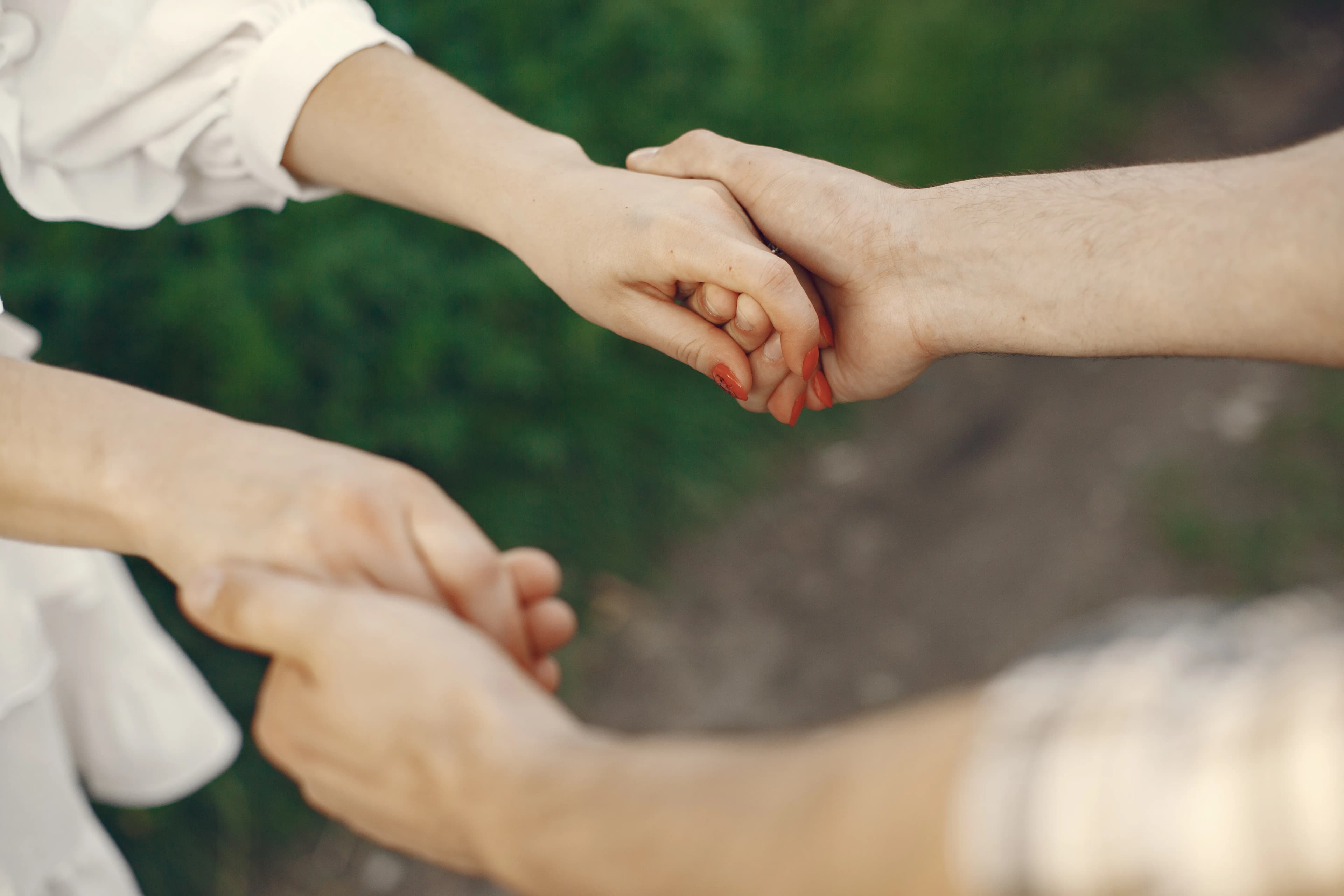 Two people holding hands outdoors, symbolizing connection and support.