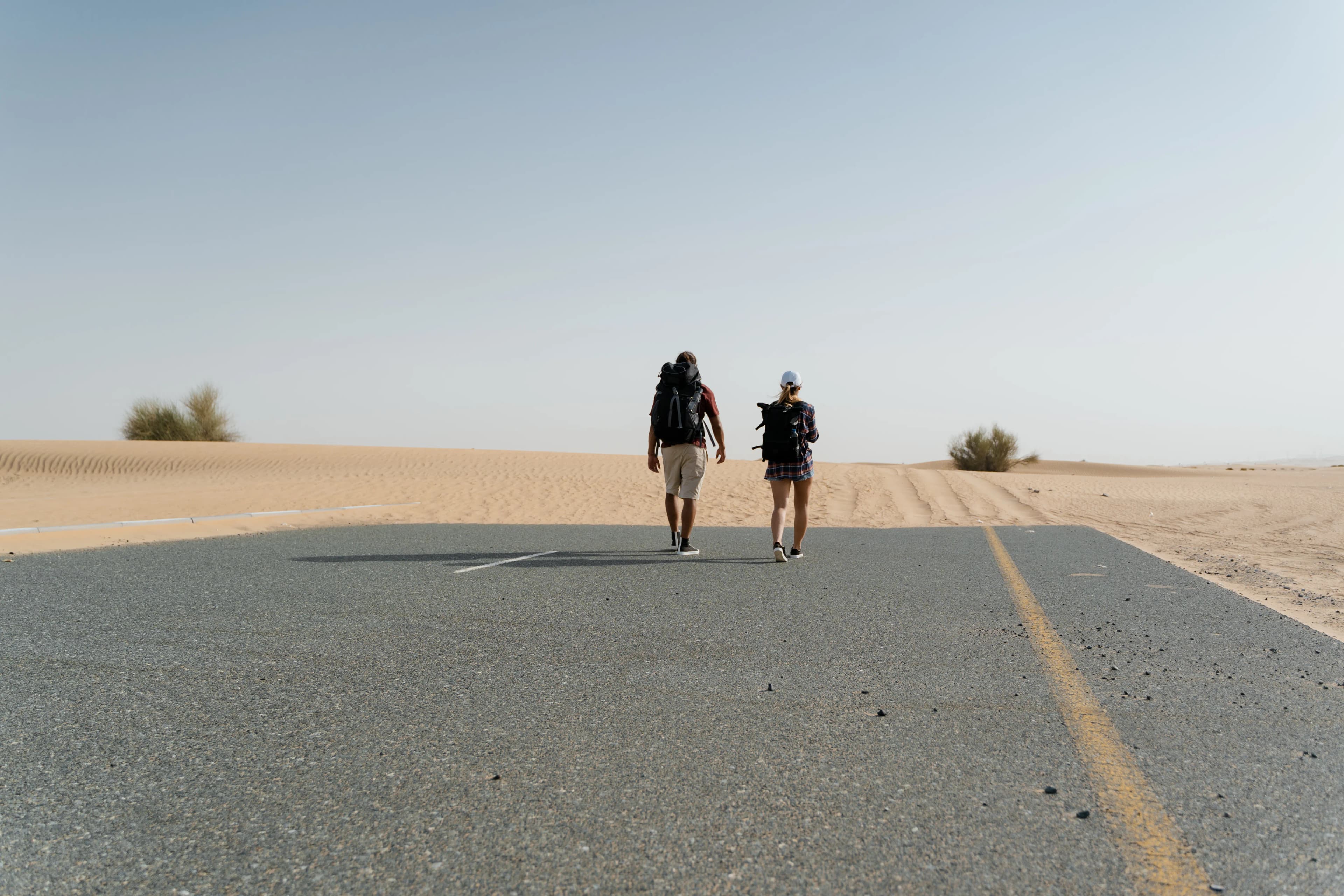 Travelers walking on an empty road through the desert