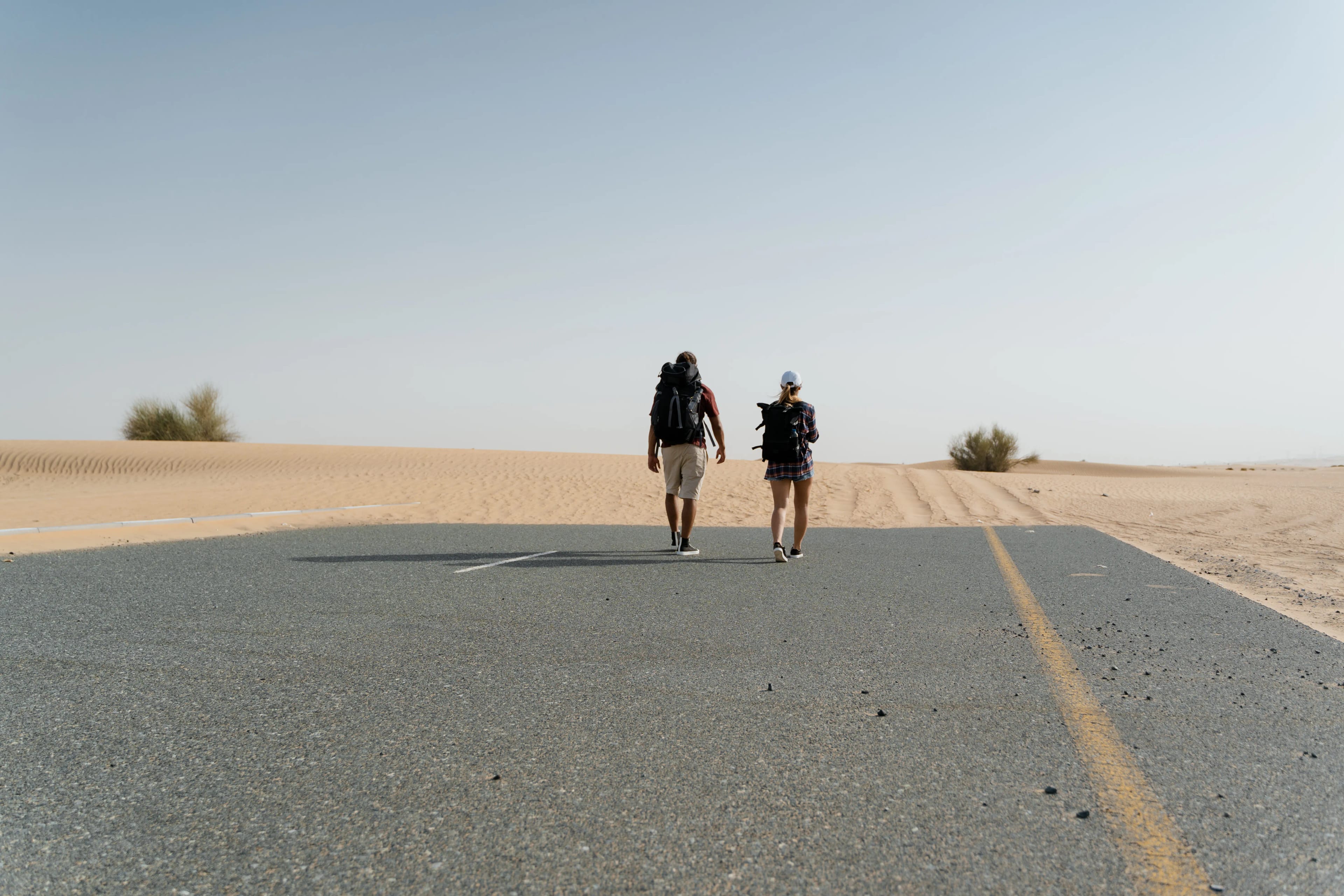 Travelers walking on an empty road through the desert